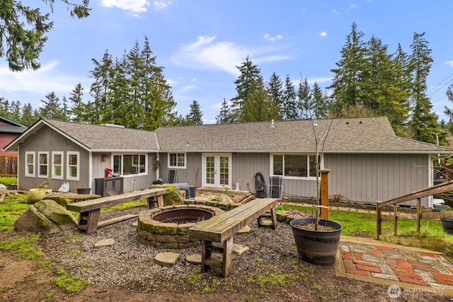 back of house featuring french doors, a fire pit, and a shingled roof