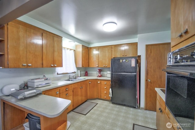 kitchen with open shelves, oven, light countertops, freestanding refrigerator, and a sink