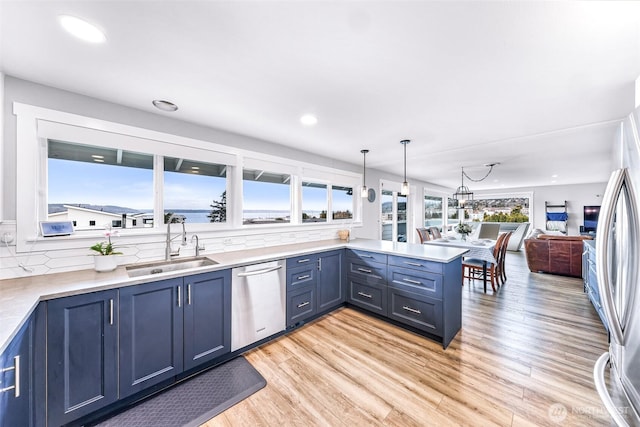 kitchen with a sink, blue cabinetry, appliances with stainless steel finishes, and a peninsula