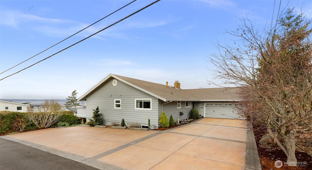 view of front facade featuring an attached garage, a chimney, and concrete driveway