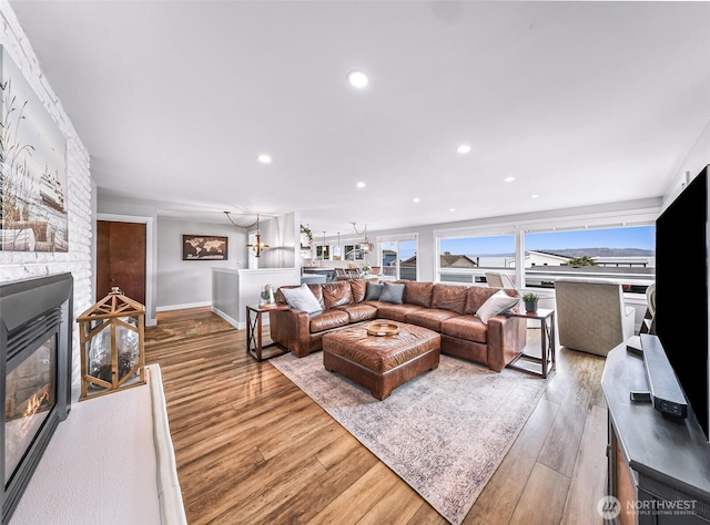 living area with a stone fireplace, recessed lighting, baseboards, and wood finished floors