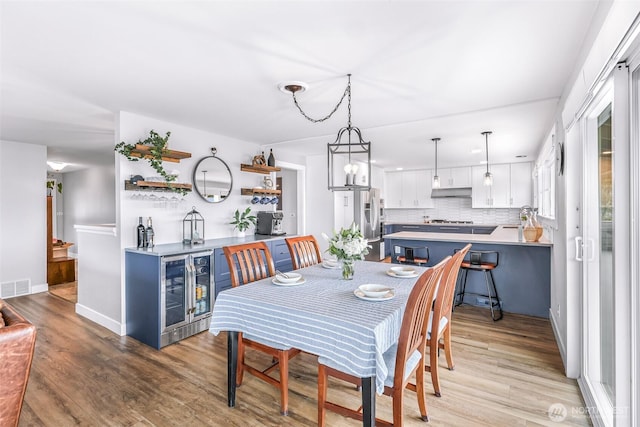 dining space with visible vents, wine cooler, baseboards, and light wood-style flooring