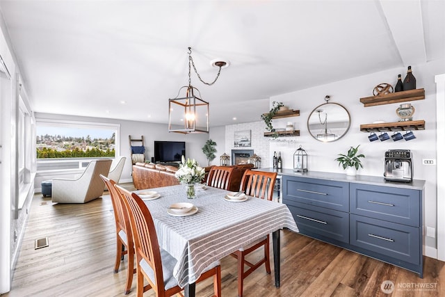 dining room with dark wood-type flooring, recessed lighting, and a fireplace