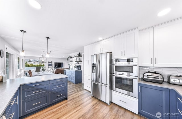 kitchen featuring light wood-type flooring, blue cabinetry, white cabinets, appliances with stainless steel finishes, and open floor plan