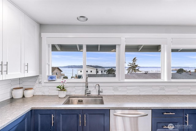 kitchen featuring decorative backsplash, dishwasher, blue cabinets, and a sink