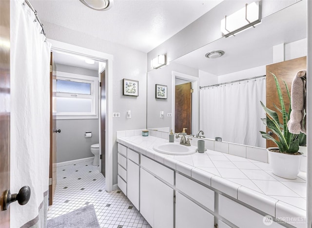 bathroom with tile patterned flooring, toilet, vanity, and baseboards