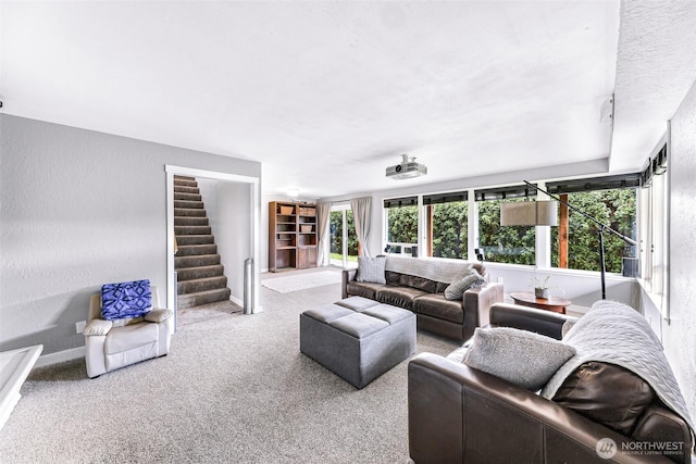 carpeted living area featuring stairs, baseboards, and a textured wall