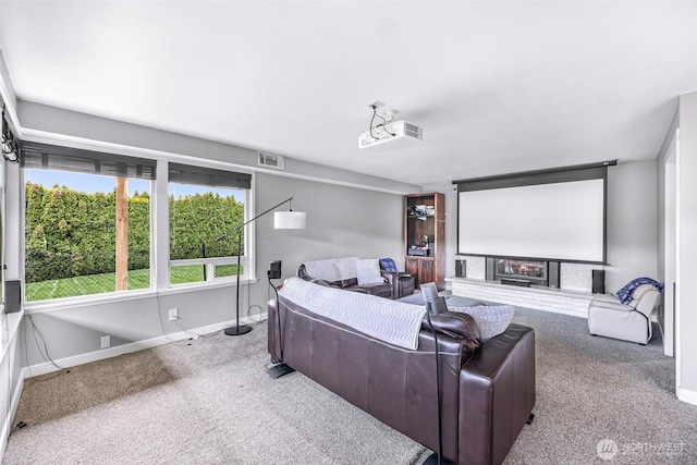 carpeted cinema featuring visible vents, baseboards, and a glass covered fireplace