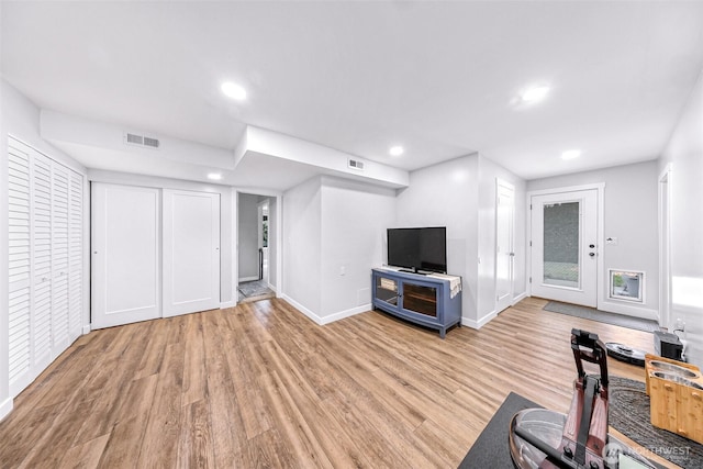 living room featuring light wood-type flooring, visible vents, baseboards, and recessed lighting