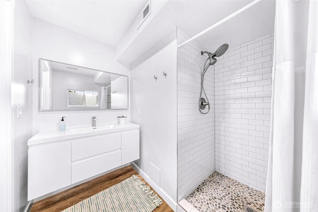 bathroom with vanity, wood finished floors, visible vents, baseboards, and a shower stall