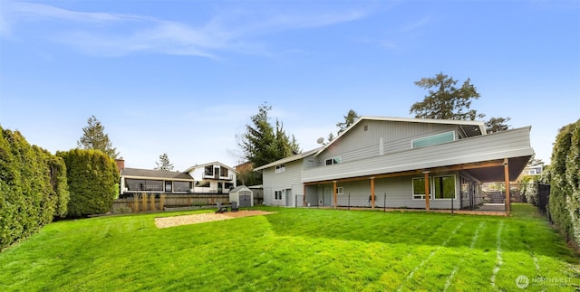 rear view of house with an outbuilding, a storage shed, a fenced backyard, and a lawn