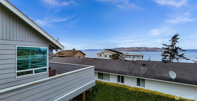 view of home's exterior with a balcony, a water view, and roof with shingles