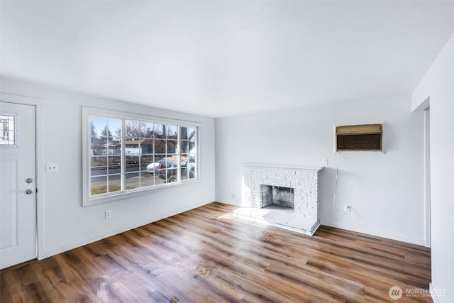 unfurnished living room featuring a brick fireplace and wood finished floors