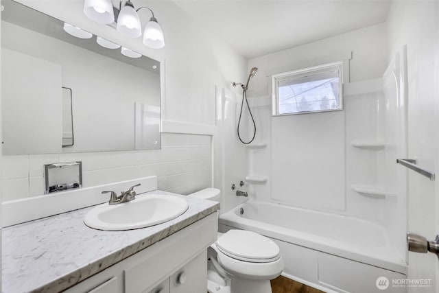 bathroom featuring shower / washtub combination, vanity, toilet, and tile walls