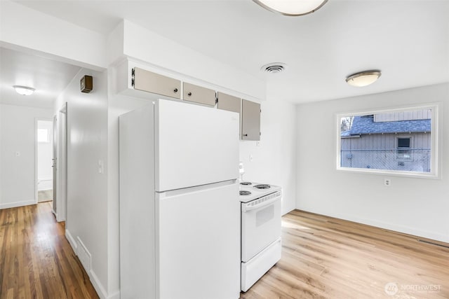 kitchen featuring visible vents, white appliances, baseboards, and light wood-style flooring