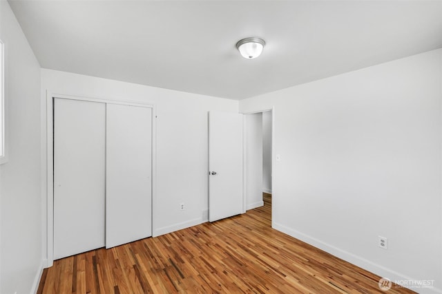 unfurnished bedroom with a closet, baseboards, and wood finished floors