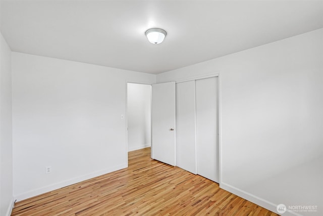 unfurnished bedroom featuring light wood-type flooring, baseboards, and a closet