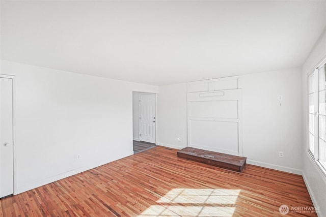 spare room with baseboards and wood finished floors