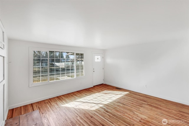 foyer entrance featuring visible vents, baseboards, and wood finished floors