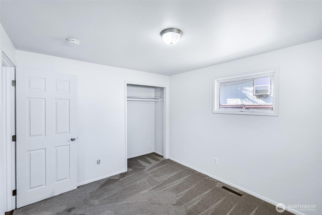 unfurnished bedroom with carpet flooring, baseboards, visible vents, and a closet