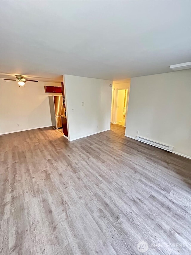 unfurnished living room featuring a ceiling fan, wood finished floors, baseboards, and a baseboard radiator