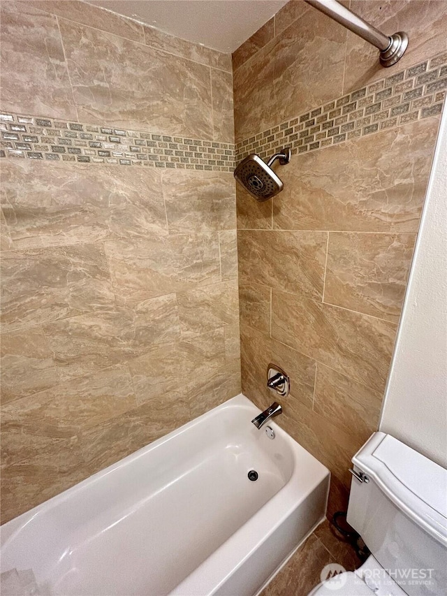 bathroom with bathtub / shower combination and toilet