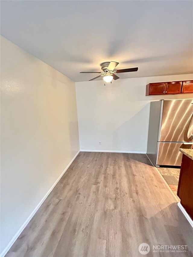 unfurnished living room with ceiling fan, baseboards, and light wood-style floors