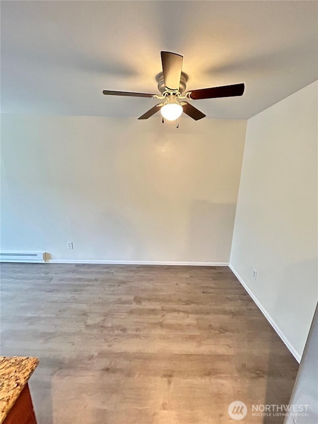 spare room featuring a ceiling fan, wood finished floors, baseboards, and baseboard heating