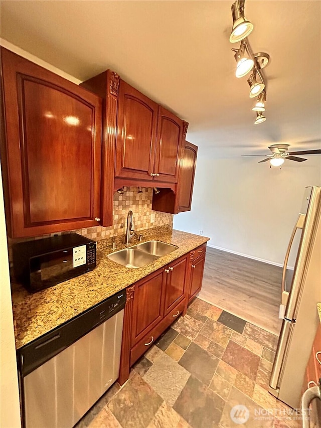 kitchen with a ceiling fan, stone finish floor, a sink, appliances with stainless steel finishes, and decorative backsplash