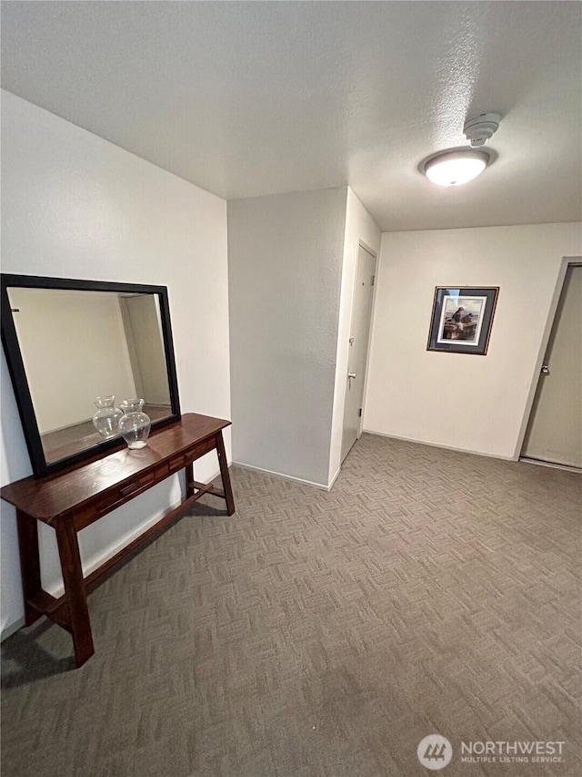 hallway featuring carpet flooring and a textured ceiling