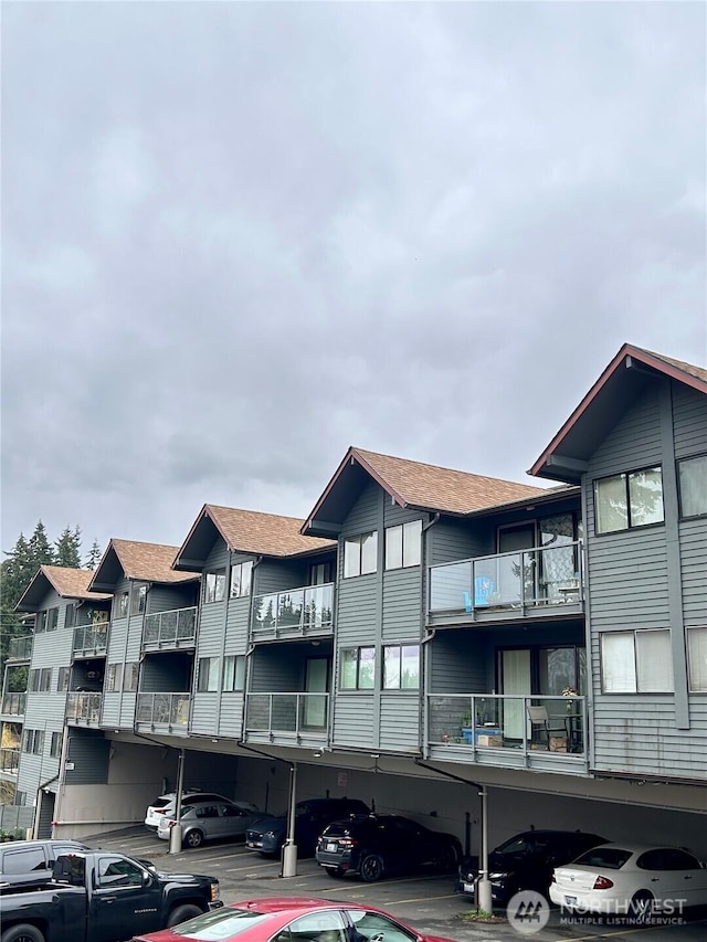 view of building exterior featuring covered and uncovered parking