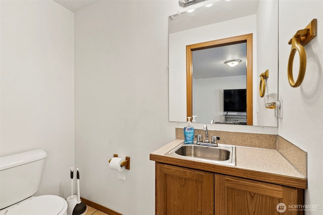 half bathroom with vanity, toilet, baseboards, and visible vents