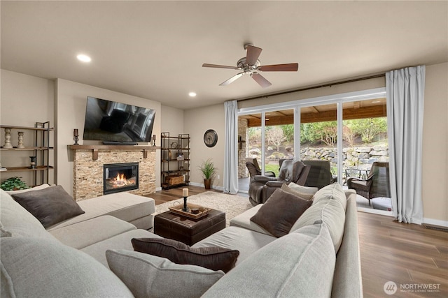 living area with a stone fireplace, recessed lighting, and wood finished floors