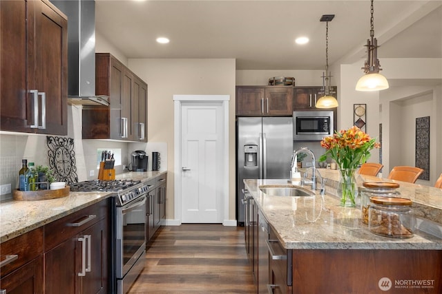 kitchen with a sink, wall chimney range hood, decorative backsplash, stainless steel appliances, and a kitchen island with sink