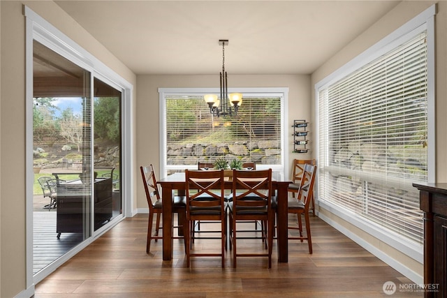 dining space featuring a chandelier, baseboards, and dark wood finished floors