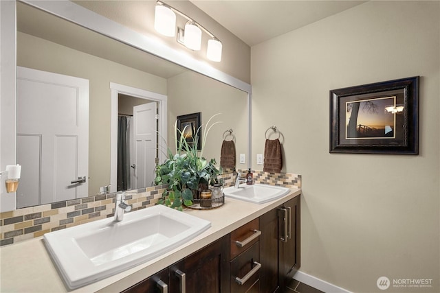 full bathroom with double vanity, decorative backsplash, baseboards, and a sink