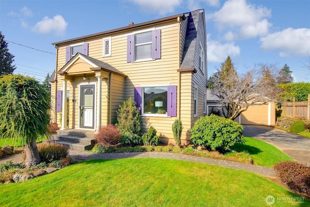 traditional-style home featuring a detached garage, an outdoor structure, a front lawn, and fence