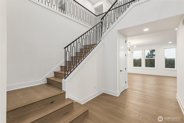 stairway with recessed lighting, baseboards, a towering ceiling, and hardwood / wood-style flooring