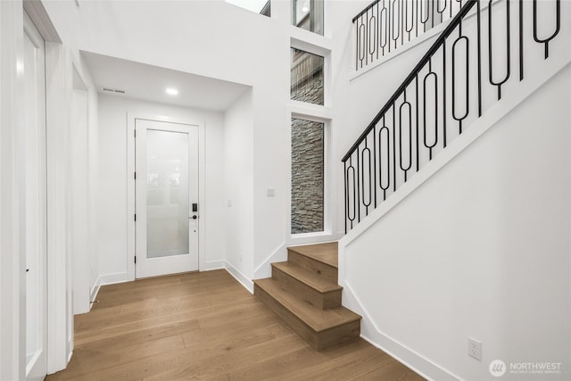 entryway with baseboards, stairs, recessed lighting, a towering ceiling, and wood finished floors