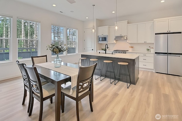 dining space featuring baseboards, light wood-type flooring, and recessed lighting