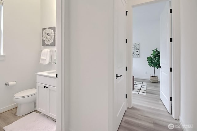 bathroom featuring toilet, vanity, wood finished floors, and baseboards