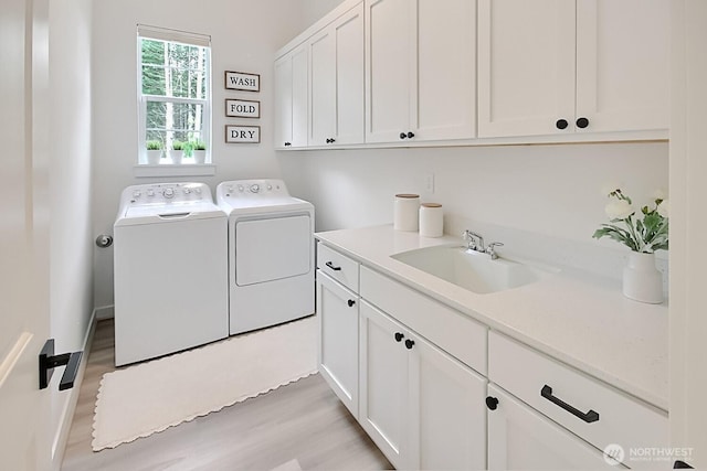 laundry area featuring a sink, light wood-type flooring, cabinet space, and washer and dryer