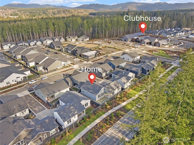 drone / aerial view featuring a view of trees, a mountain view, and a residential view