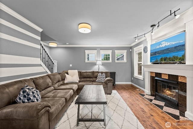 living area featuring baseboards, stairway, ornamental molding, a premium fireplace, and wood finished floors