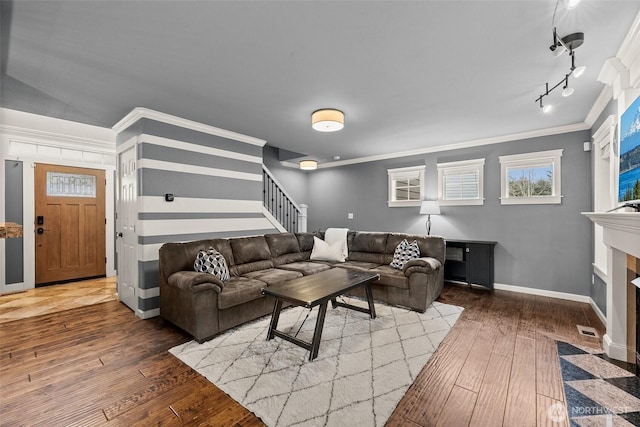 living area featuring a fireplace with flush hearth, ornamental molding, hardwood / wood-style flooring, stairway, and baseboards