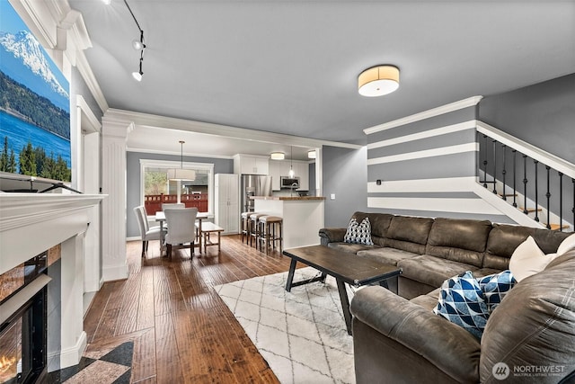 living room featuring hardwood / wood-style flooring, stairway, crown molding, and a high end fireplace