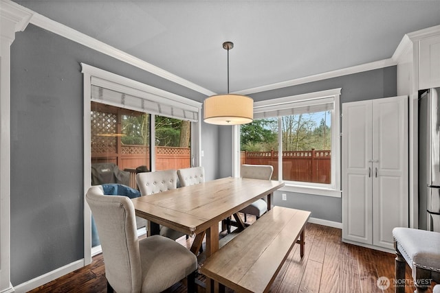 dining room with dark wood finished floors, ornate columns, baseboards, and ornamental molding