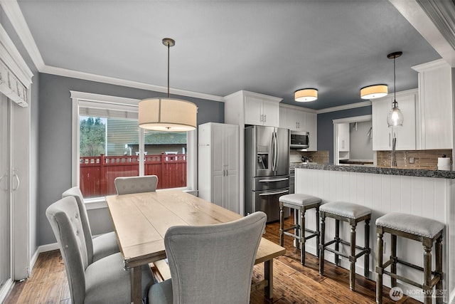 dining room featuring crown molding, baseboards, and wood-type flooring