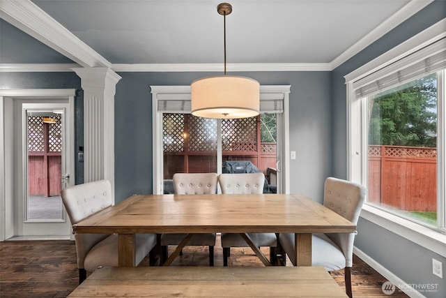 dining room with crown molding, dark wood-style floors, baseboards, and ornate columns