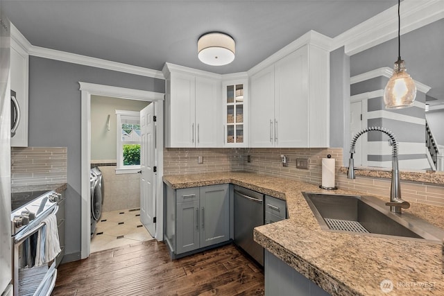 kitchen featuring white cabinetry, washing machine and clothes dryer, appliances with stainless steel finishes, and a sink